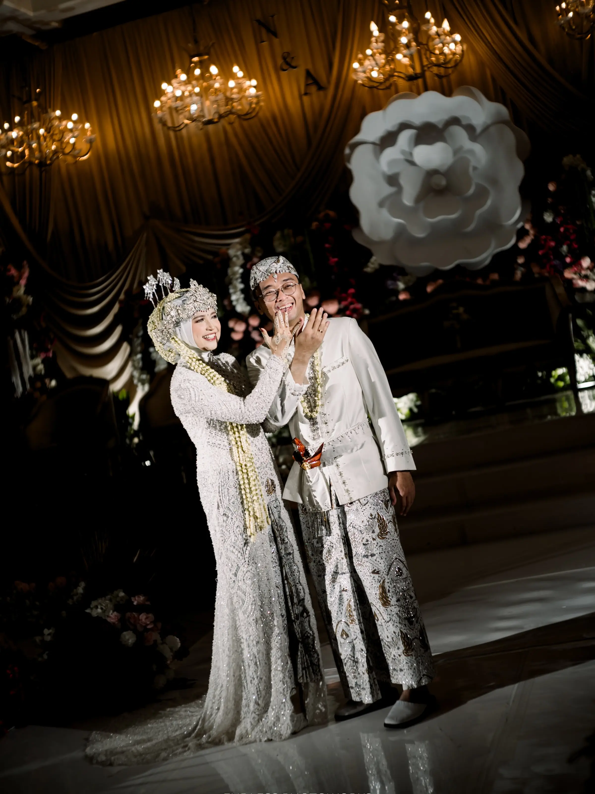 Sepasang pengantin berbusana putih adat Sunda di depan pelaminan