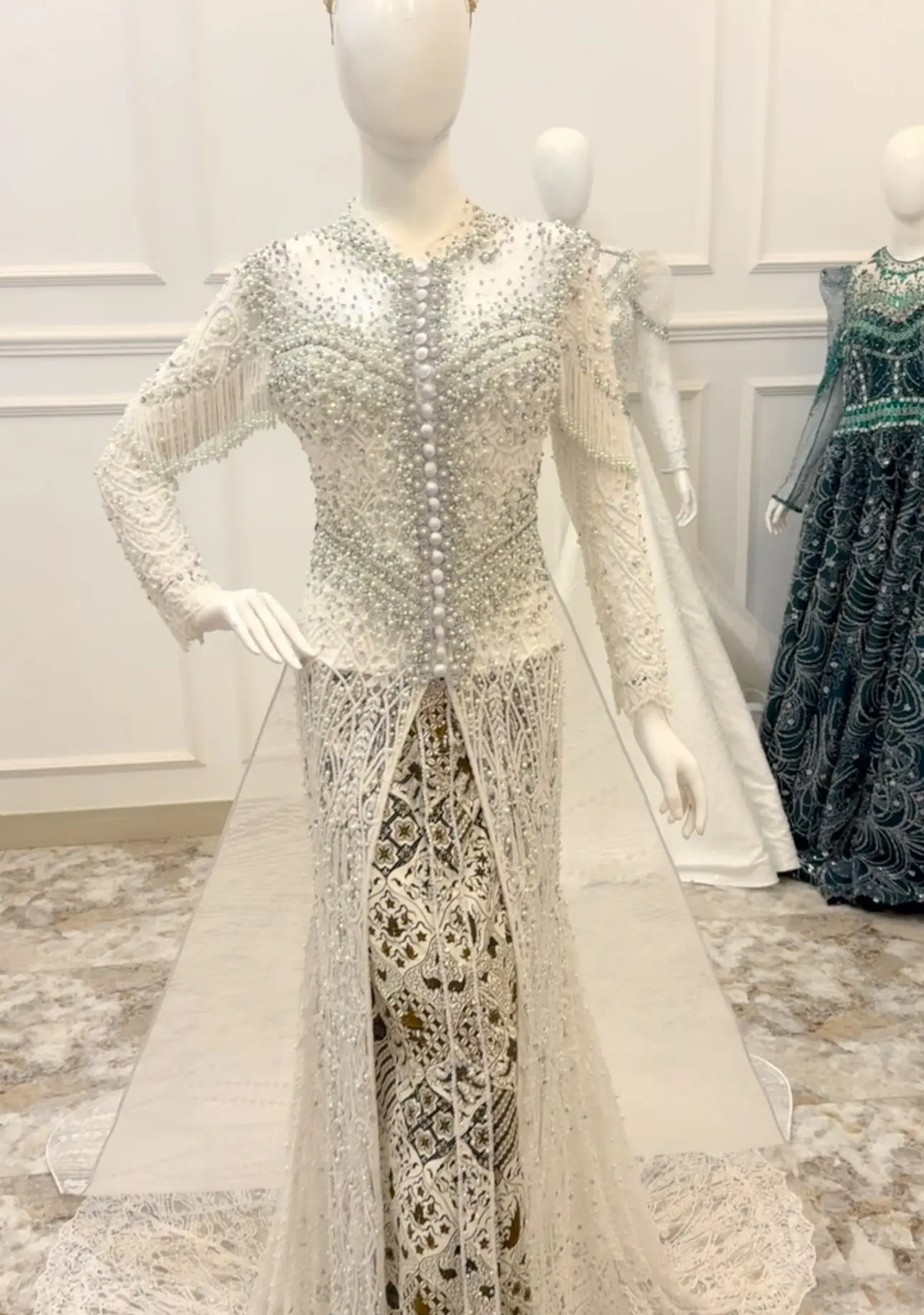 Kebaya putih berpayet dengan kain batik di manekin