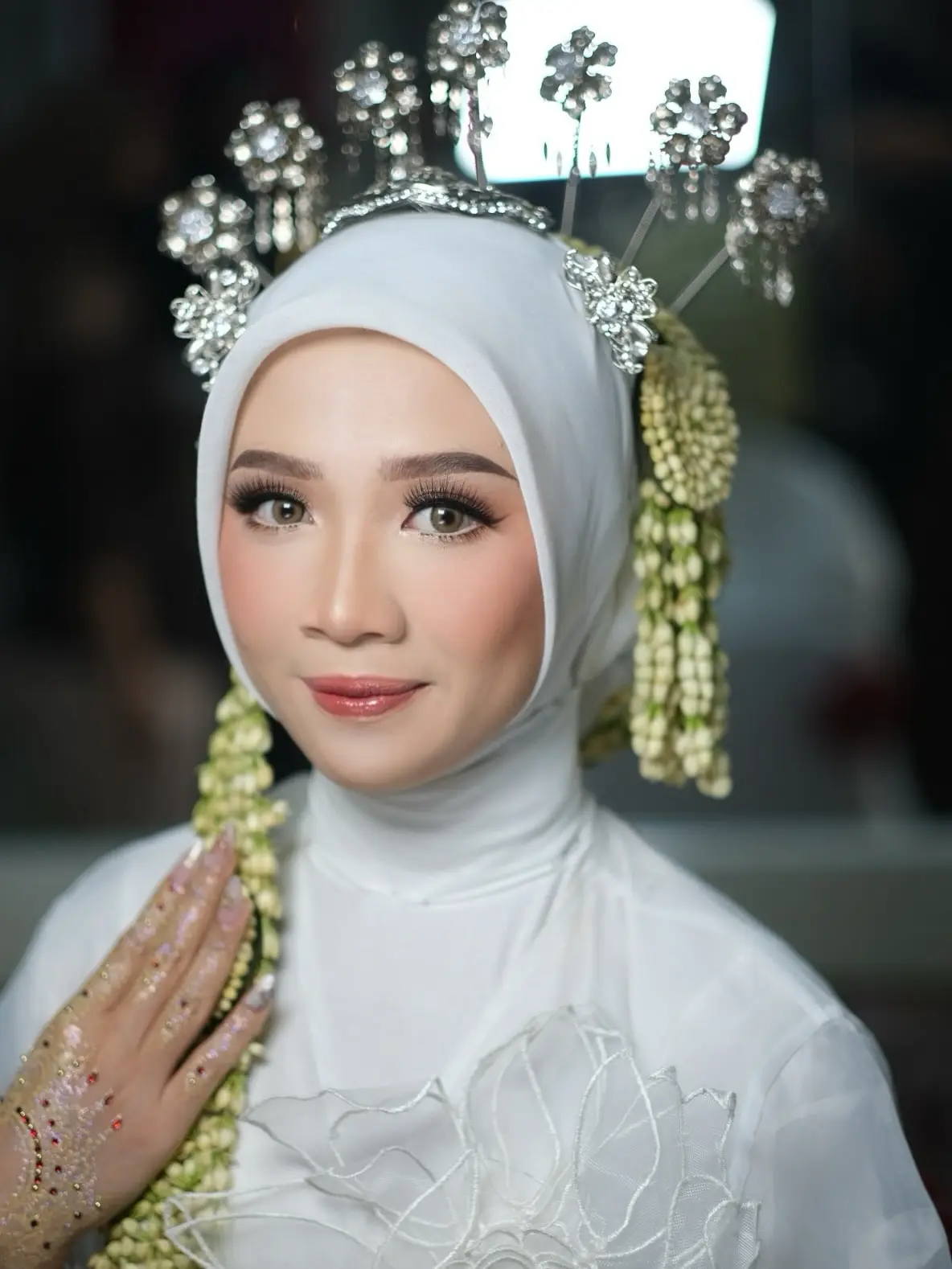 Pengantin berhijab putih dengan siger dan ronce melati, dirias oleh Asih Wedding